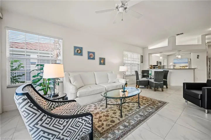 Tiled living room with ceiling fan, a wealth of natural light, and vaulted ceiling
