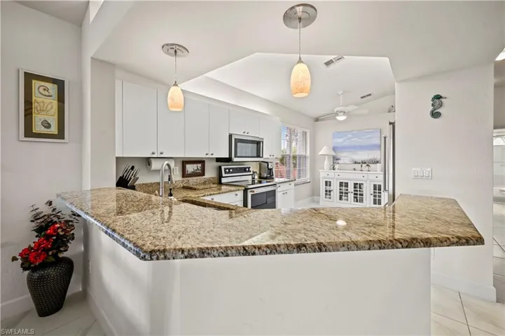 Kitchen featuring kitchen peninsula, stone countertops, light tile patterned floors, and stainless steel appliances