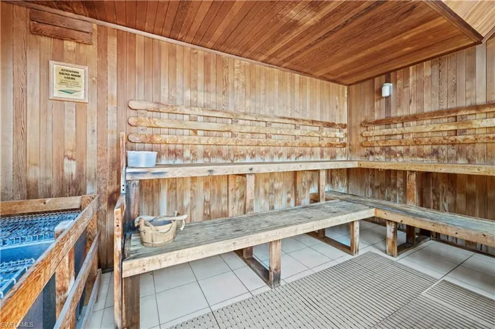 View of sauna with wood walls, wooden ceiling, and tile patterned floors