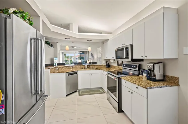Kitchen with kitchen peninsula, stainless steel appliances, pendant lighting, and white cabinetry