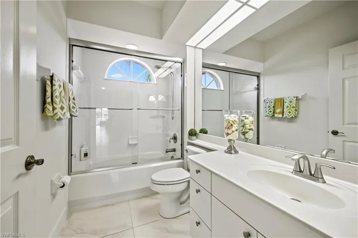 Full bathroom featuring toilet, combined bath / shower with glass door, vanity, and tile patterned floors