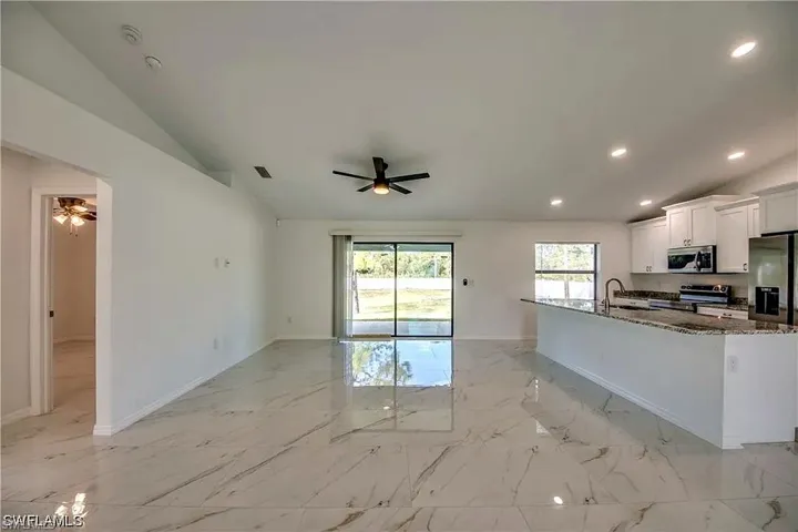 Spacious interior featuring a vaulted ceiling and polished tile flooring