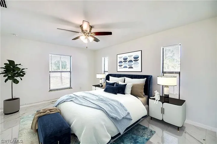 White walls with multiple windows, contemporary ceiling fan, and reflective tile flooring