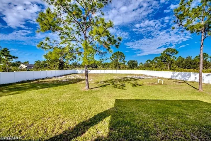 Expansive lawn area with a white privacy fence