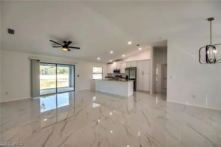 Polished tile flooring, vaulted ceilings, recessed lighting, ceiling fan, and sliding glass door to outdoor area