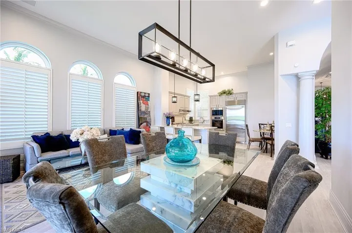 Dining area with light hardwood / wood-style flooring, a towering ceiling, crown molding, and ornate columns