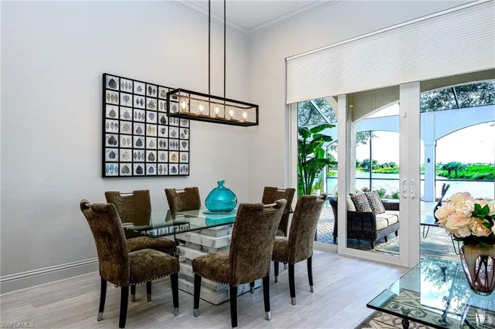 Dining room with light wood-type flooring, ornamental molding, and an inviting chandelier