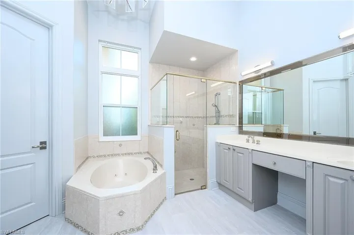 Bathroom featuring shower with separate bathtub, double sink vanity, and tile patterned floors