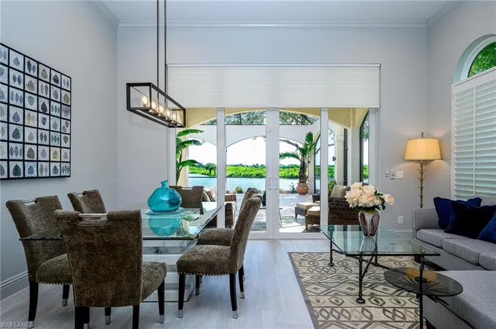 Dining area featuring a water view, french doors, crown molding, and light hardwood / wood-style flooring