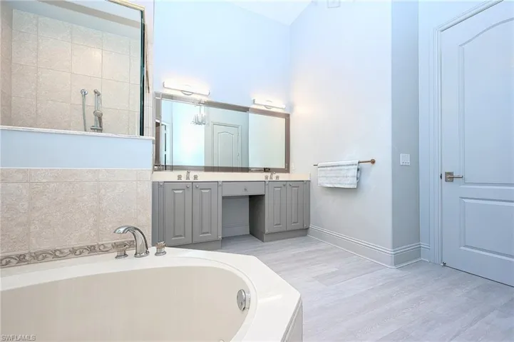 Bathroom featuring hardwood / wood-style floors, a bathtub, and dual vanity