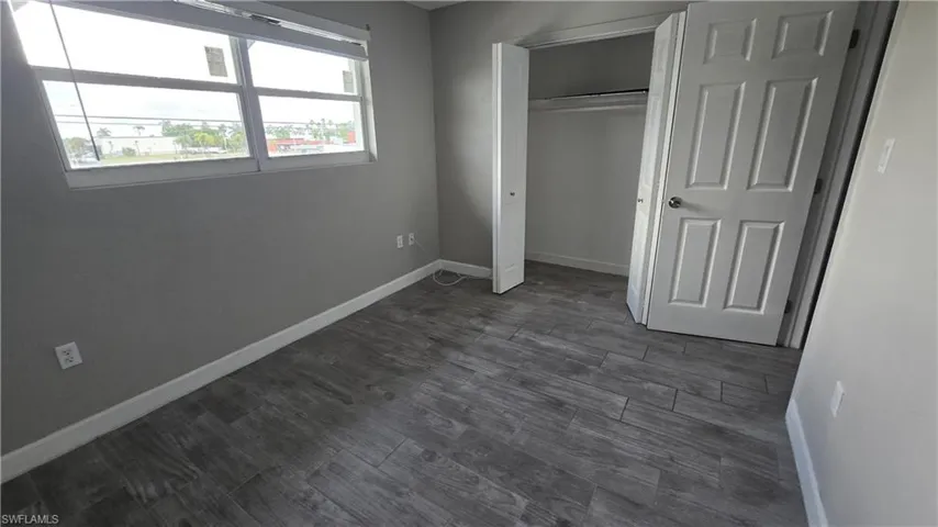 Unfurnished bedroom with dark wood-style floors and a closet