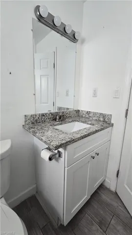 Half bathroom with vanity and wood finish floors