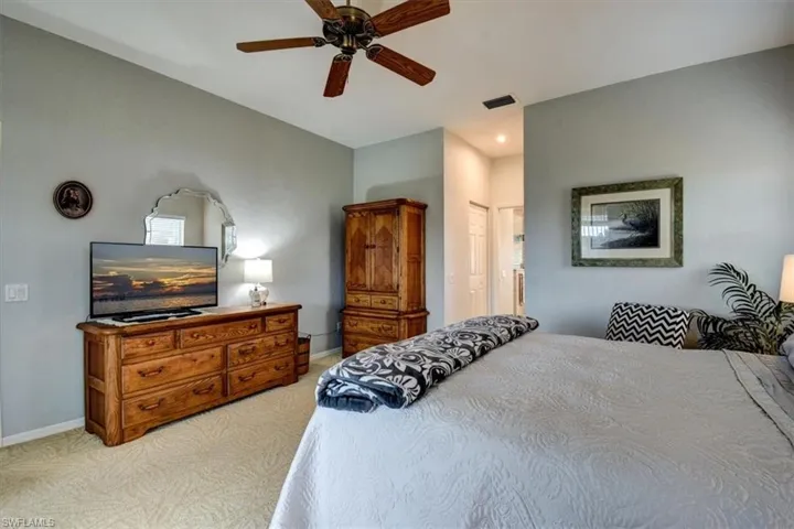 Bedroom with ceiling fan, light colored carpet, and a closet