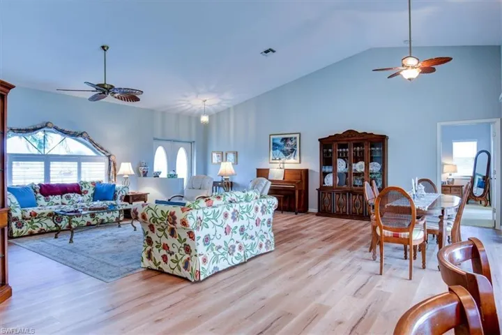 Living area with ceiling fan, wood finished floors, and high vaulted ceiling