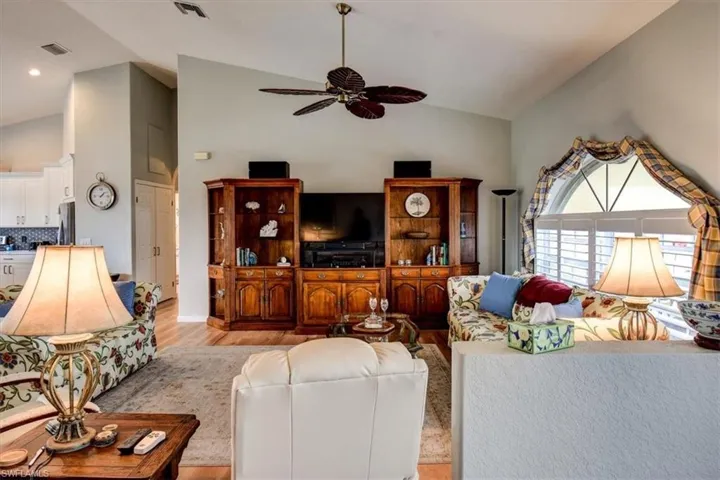 Living area with vaulted ceiling, light wood-style flooring, and a ceiling fan