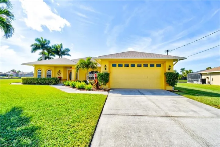 View of front of house with stucco siding, a front yard, concrete driveway, and an attached garage