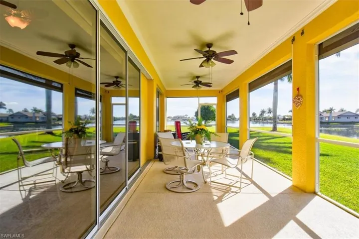 Sunroom with a water view, outdoor dining space, ceiling fan, and a residential view