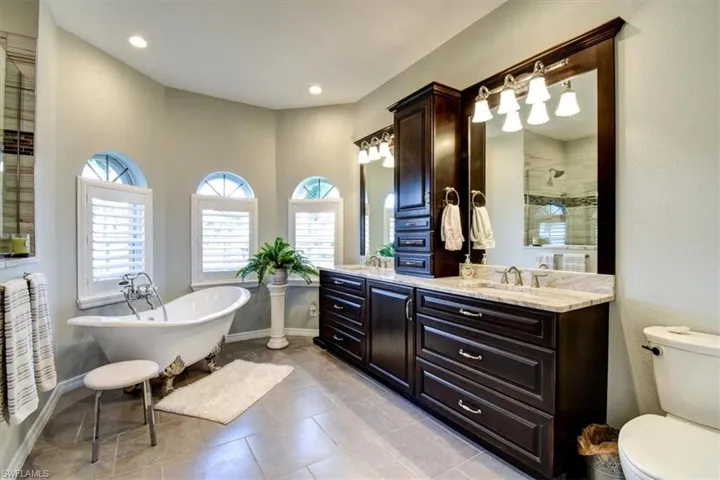 Bathroom featuring vanity, a freestanding bath, light tile patterned flooring, and an enclosed shower