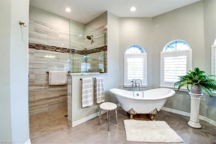 Full bathroom featuring walk in shower, a soaking tub, and tile patterned floors