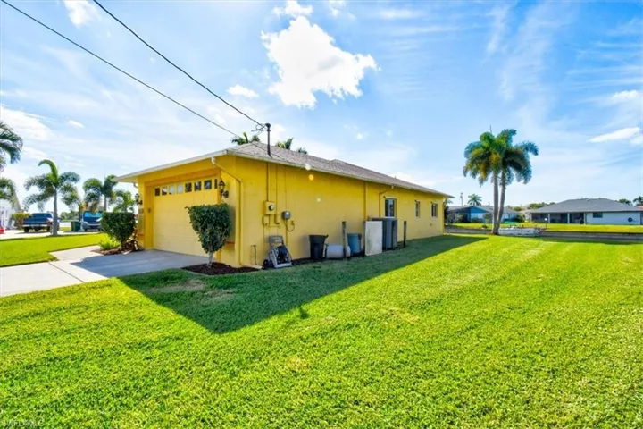 View of side of property featuring a yard, concrete driveway, and stucco siding