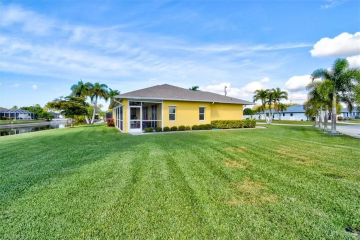 Back of property with a sunroom, a yard, and stucco siding