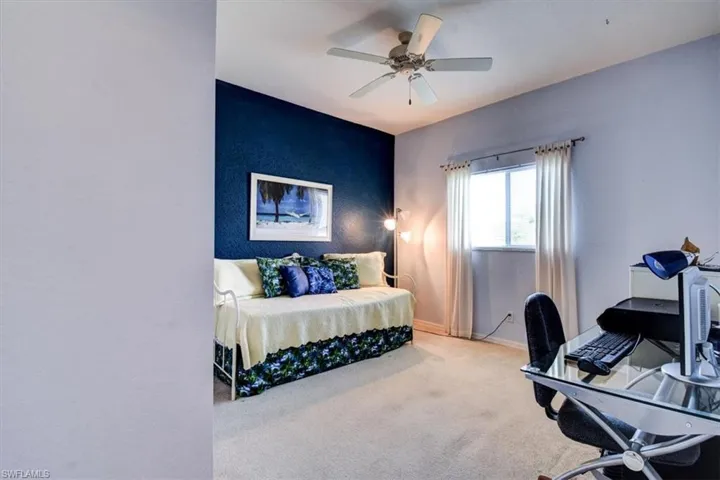 Carpeted bedroom featuring an office area and a ceiling fan