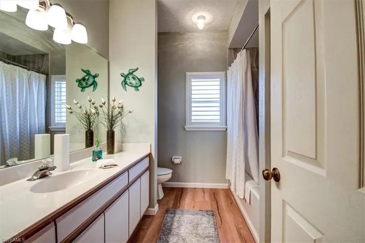 Full bathroom featuring vanity, light wood-type flooring, and shower / bath combo with shower curtain