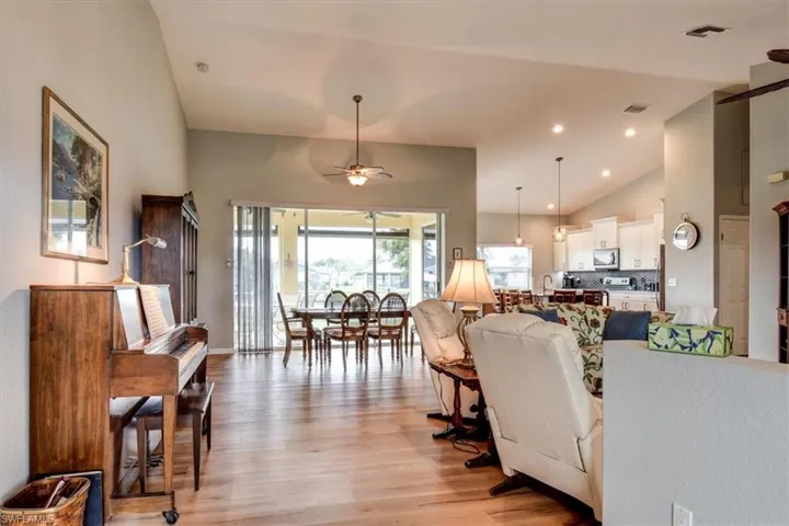Living room featuring light wood-style flooring, a ceiling fan, high vaulted ceiling, and recessed lighting