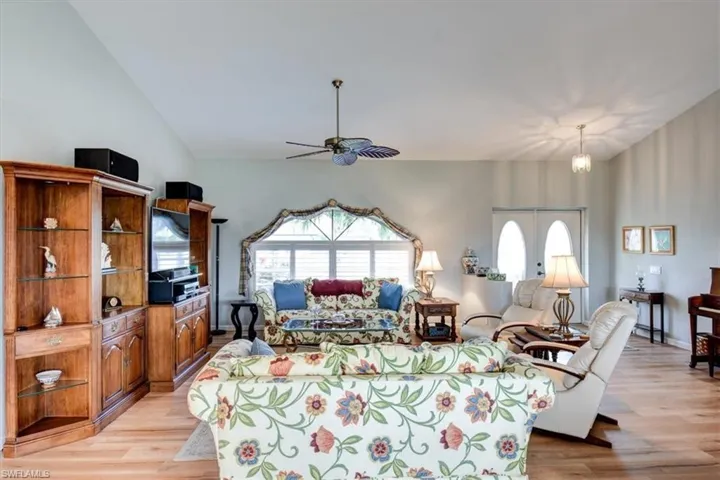 Living room featuring plenty of natural light, light wood-type flooring, a ceiling fan, and lofted ceiling