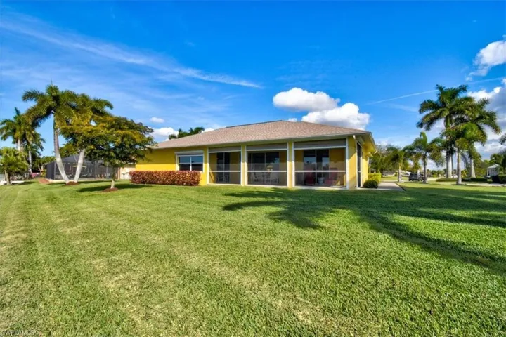 Rear view of property with a sunroom and a lawn