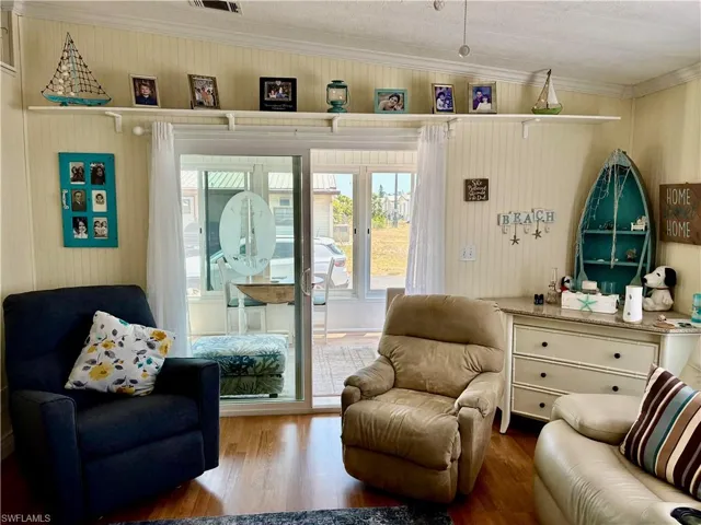 Sitting room featuring wood finished floors, visible vents, and crown molding