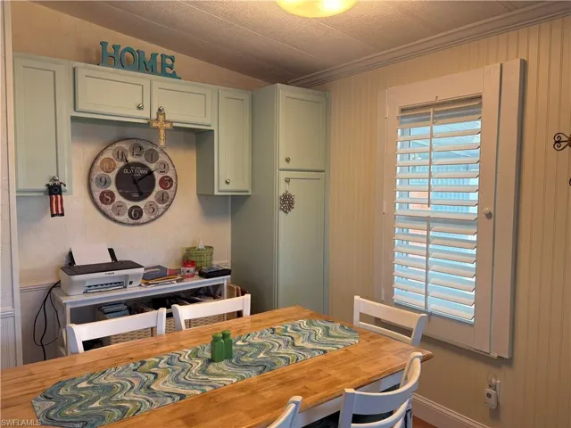 Dining area featuring lofted ceiling, wood walls, and ornamental molding