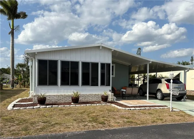 View of front facade with concrete driveway, a front lawn, and an attached carport