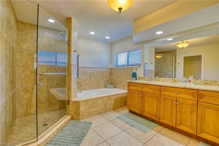 Full bathroom with vanity, a bath, light tile patterned floors, a stall shower, and recessed lighting