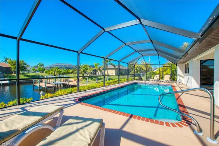 Swimming pool featuring a sunroom, a lanai, a patio area, and a water view