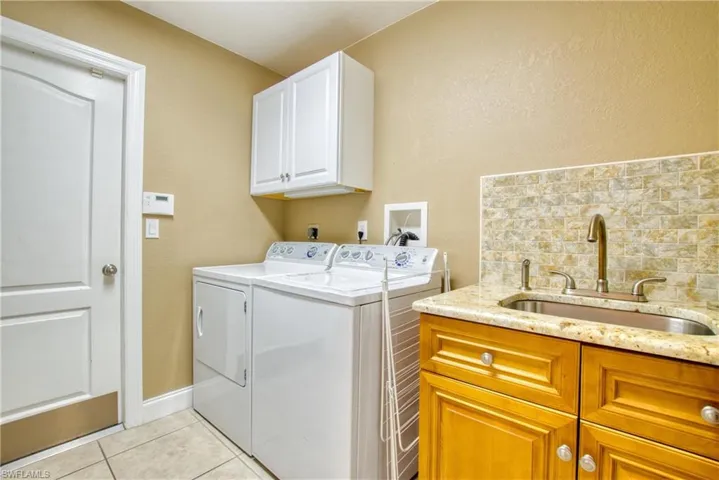 Laundry room with cabinet space, light tile patterned floors, separate washer and dryer, and a textured wall