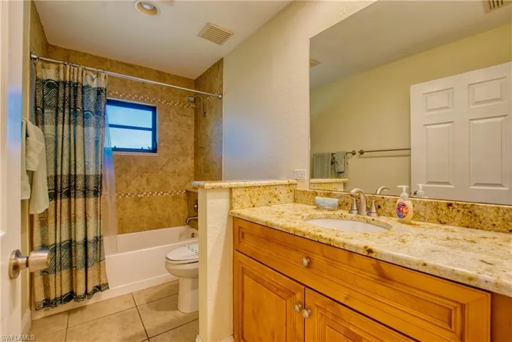 Full bath with shower / bathtub combination with curtain, vanity, and light tile patterned floors