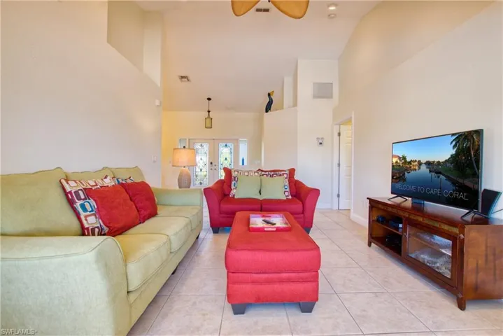 Living room featuring high vaulted ceiling, french doors, tile patterned flooring, and ceiling fan