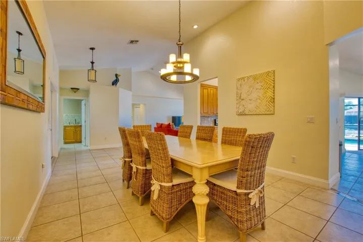 Dining space with light tile patterned flooring, high vaulted ceiling, and a chandelier