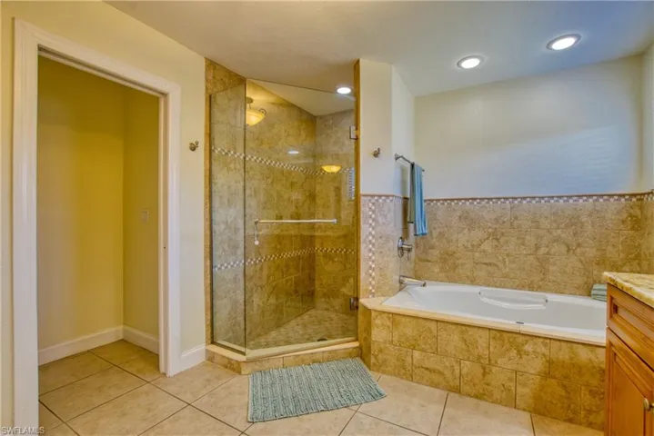 Bathroom featuring tile patterned flooring, a bath, a stall shower, vanity, and recessed lighting