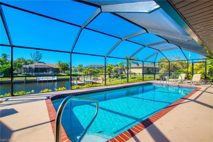 Swimming pool with a lanai, a sunroom, a water view, and a patio