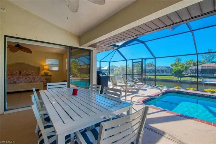 View of patio / terrace with an outdoor pool, a sunroom, glass enclosure, and a ceiling fan