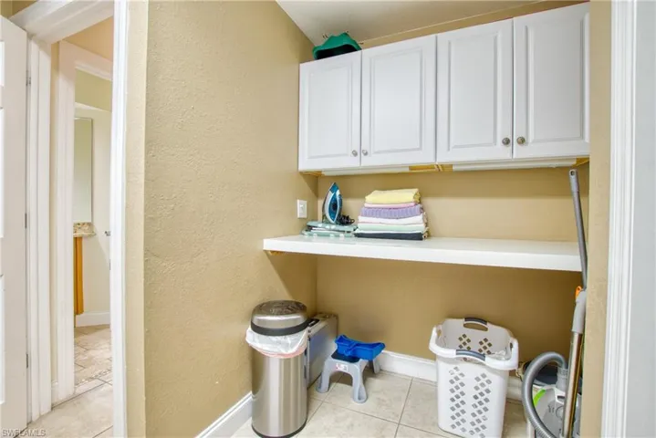 Laundry area featuring a textured wall and light tile patterned floors