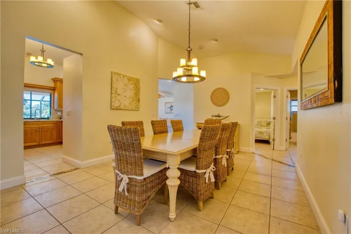 Dining area with a chandelier, light tile patterned floors, and lofted ceiling