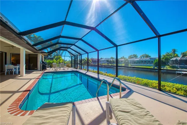 Swimming pool featuring a sunroom, glass enclosure, a water view, a patio, and ceiling fan