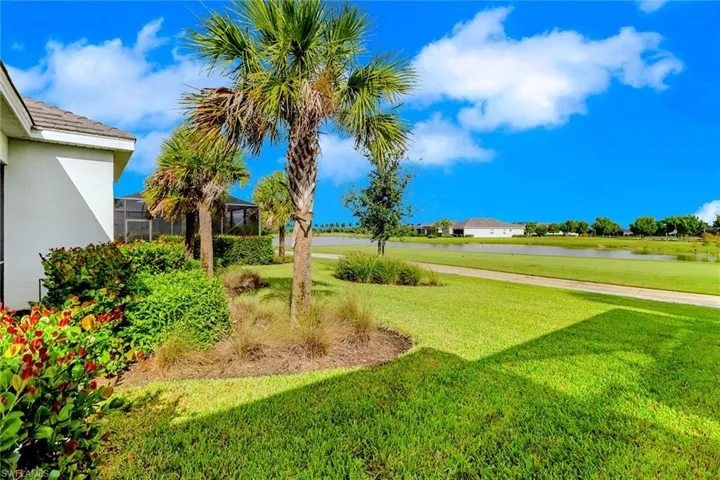 View of grassy yard with a water view and a lanai