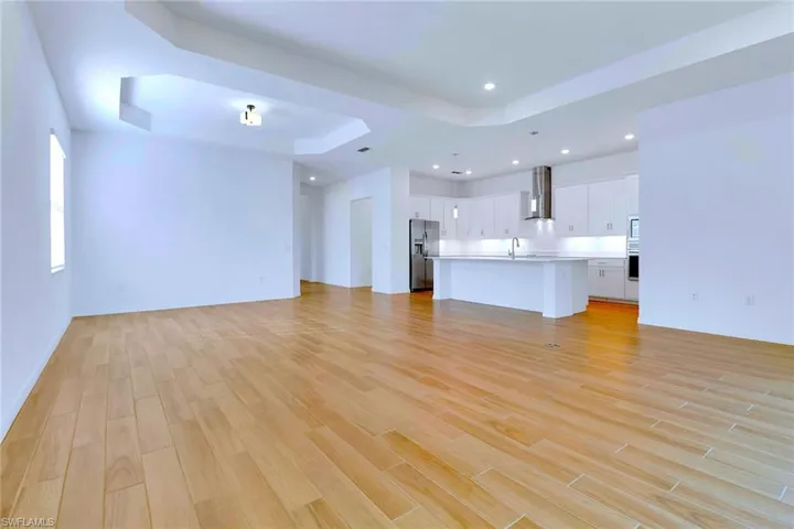 Unfurnished living room featuring a tray ceiling, light wood-style flooring, and recessed lighting