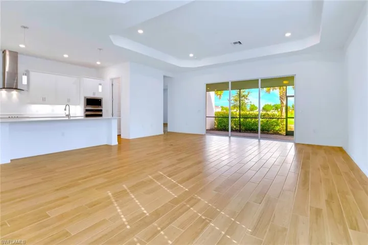 Unfurnished living room featuring a tray ceiling, recessed lighting, a skylight, and light wood-type flooring