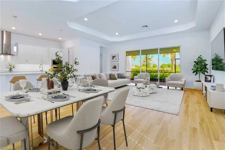 Dining space featuring a raised ceiling, recessed lighting, light wood-style floors, and a skylight