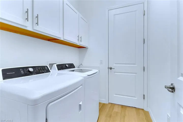 Laundry room featuring light wood-style floors, cabinet space, and washer and dryer